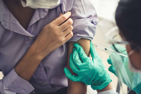 Young woman visits skillful doctor at hospital for vaccination . Covid 19 and coronavirus vaccination center service concept .の写真素材