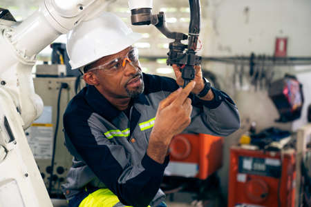 African American factory worker working with adept robotic arm in a workshop . Industry robot programming software for automated manufacturing technology .の写真素材