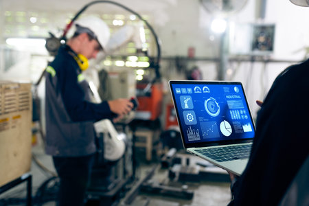 Factory workers working with adept robotic arm in a workshop . Industry robot programming software...