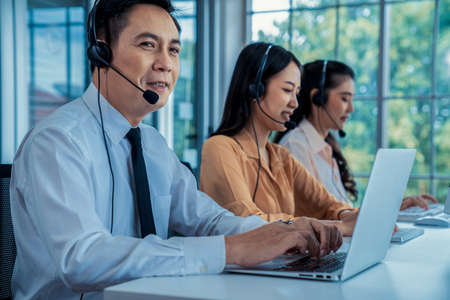 Business people wearing headset working actively in office . Call center, telemarketing, customer support agent provide service on telephone video conference call.の写真素材