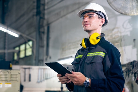 Young factory worker using adept tablet computer in a workshop building . Industrial technology and...
