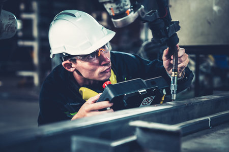 Young factory worker working with adept robotic arm in a workshop . Industry robot programming...