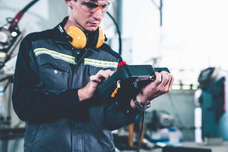 Young factory worker working with adept robotic arm in a workshop . Industry robot programming software for automated manufacturing technology .の写真素材