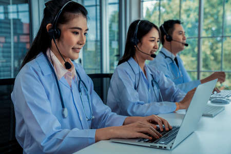 Doctor team wearing headset talking actively on video call in hospital clinic . Concept of telehealth and telemedicine service .の写真素材