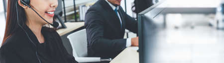 Call center or customer support agent in broaden view panorama banner wearing headset while working at office to support remote customer or colleague on telephone video conference callの写真素材