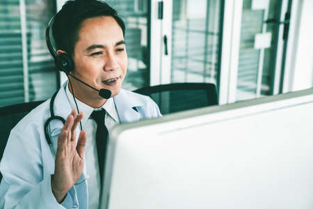 Doctor wearing headset talking actively on video call in a clinic or hospital . Concept of telehealth and telemedicine service .の写真素材