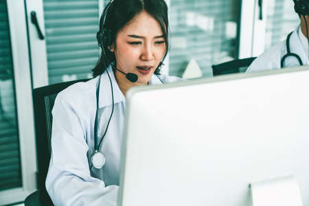Doctor wearing headset talking actively on video call in hospital or clinic . Concept of telehealth and telemedicine service .の写真素材