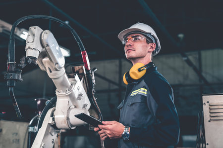 Young factory worker working with adept robotic arm in a workshop . Industry robot programming...