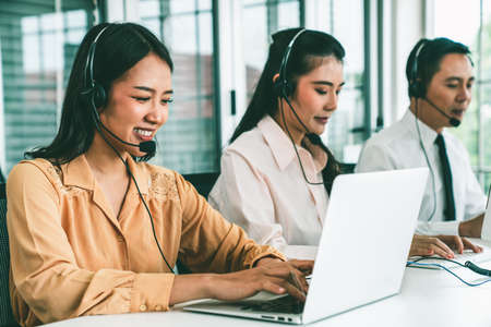 Business people wearing headset working actively in office . Call center, telemarketing, customer support agent provide service on telephone video conference call.の写真素材