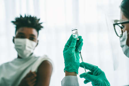 Young man visits skillful doctor at hospital for vaccination . Covid 19 and coronavirus vaccination center service concept .の写真素材