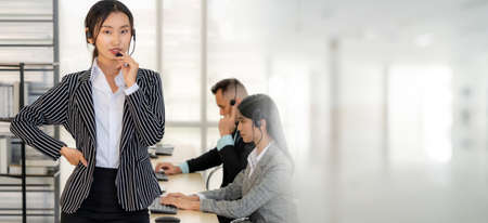 Business people wearing headset working in office to support remote customer or colleague. Call center, telemarketing, customer support agent provide service in broaden view .の写真素材