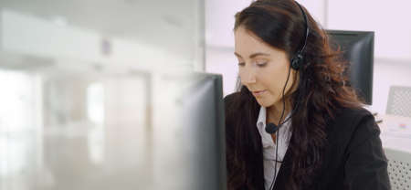 Business people wearing headset working in office to support remote customer or colleague. Call center, telemarketing, customer support agent provide service in broaden view .の写真素材