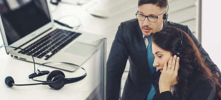 Business people wearing headset working in office to support remote customer or colleague. Call center, telemarketing, customer support agent provide service in broaden view .の写真素材