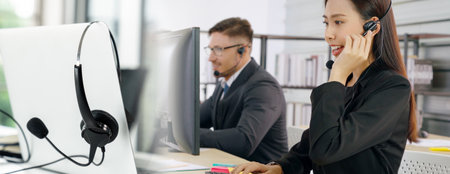 Business people wearing headset working in office to support remote customer or colleague. Call center, telemarketing, customer support agent provide service in broaden view .の写真素材