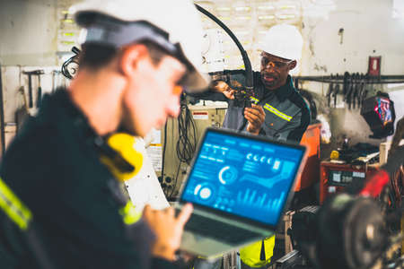Young factory worker working with adept robotic arm in a workshop . Industry robot programming software for automated manufacturing technology .の写真素材