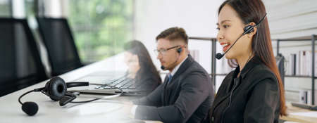 Business people wearing headset working in office to support remote customer or colleague. Call center, telemarketing, customer support agent provide service in broaden view .の写真素材