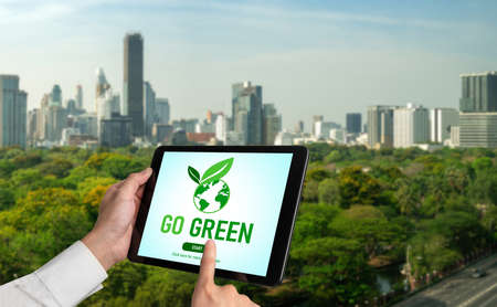 Green business transformation for environment saving and ESG business concept. Businessman using tablet to set corporate goal toward environmental friendly management and alternative clean energy use.の写真素材