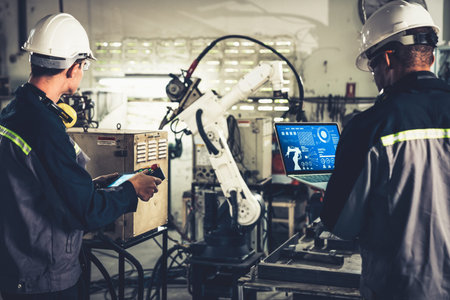 Factory workers working with adept robotic arm in a workshop . Industry robot programming software...