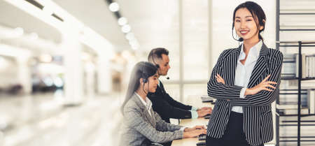 Business people wearing headset working in office to support remote customer or colleague. Call center, telemarketing, customer support agent provide service in broaden view .の写真素材