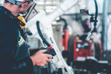 Young factory worker working with adept robotic arm in a workshop . Industry robot programming software for automated manufacturing technology .の写真素材