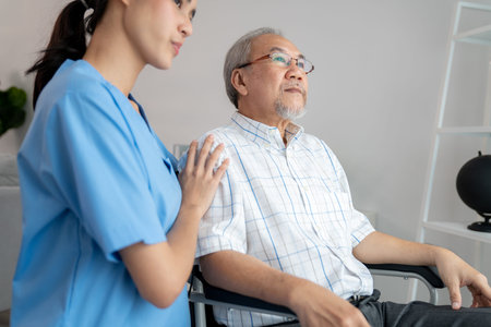 Caring nurse and a contented senior man in a wheel chair at home, nursing house. Medical for elderly patient, home care for pensioners.の写真素材