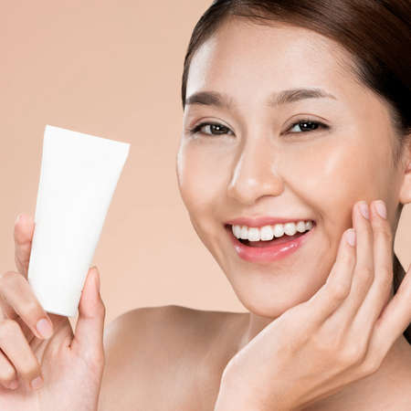 Closeup ardent woman smiling holding mockup product for advertising text place, light grey background. Concept of healthcare for skin, beauty care product for advertising.の写真素材