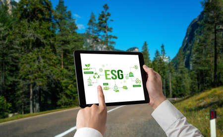 Green business transformation for environment saving and ESG business concept. Businessman using tablet to set corporate goal toward environmental friendly management and alternative clean energy use.の写真素材