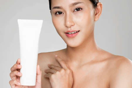 Closeup ardent woman smiling holding mockup product for advertising text place, light grey background. Concept of healthcare for skin, beauty care product for advertising.の写真素材
