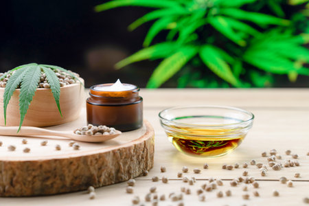 Cannabis and cosmetic concept features with set of CBD oil bottles, cream jar, and wooden bowl of hemp seeds. Legalized cannabis for skincare products.の写真素材