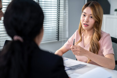 A young female asian candidate tries to impress her interviewer by being competent. International company, multicultural environment in workplace.の写真素材