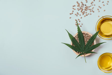 CBD oil, THC tinture in glass bowl and bottle with dropper lid and hemp leaf on empty background with a pile of dry hemp seeds surrounded in minimalism. Legalized marijuana concept.の写真素材