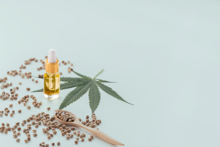 Legalized marijuana concept features with CBD oil extract from marihuana in glass bottle with dropper lid, piles of hemp seeds on empty background. Marijuana products for copyspace and advertising.の写真素材