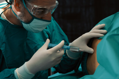 Surgeon inject anesthesia with syringe into the patient before perform surgery in sterile operation room with modern surgical equipments. Medical surgery perform by professional and confident surgeon.の写真素材