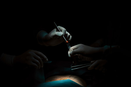 Closeup surgical team performing surgery to patient in sterile operating room. In a surgery room lit by a lamp, a professional and confident surgical team provides medical care to unconscious patient.の写真素材