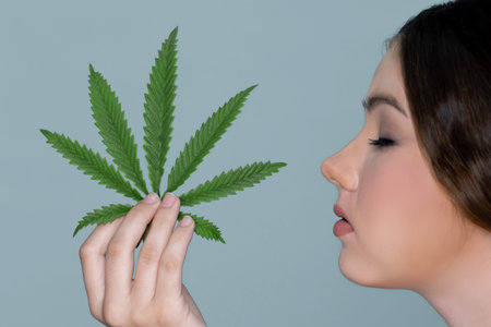 Closeup charming girl with fresh skin hold green leaf for beauty skin care made from cannabis leaf....