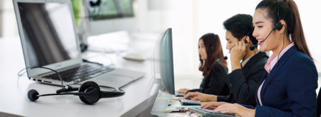 Business people wearing headset working in office in widen view to support remote customer or colleague. Call center, telemarketing, customer support agent provide service on telephone video call.の写真素材