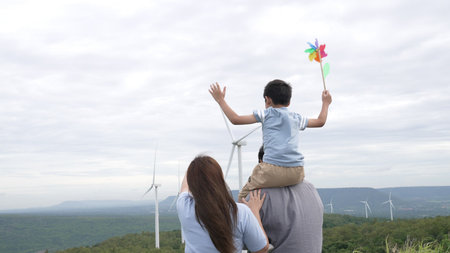 Concept of progressive happy family enjoying their time at the wind turbine farm. Electric generator...