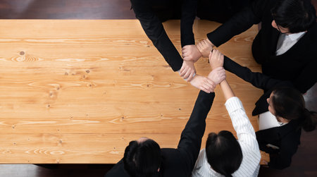 Top view cohesive group of business people join hands stack together, form circle over meeting table for copyspace. Colleagues working to promote harmony and synergy team building concept in workplaceの写真素材