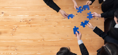 Top view businesspeople and colleagues in formal wear putting jigsaw puzzles together over meeting...