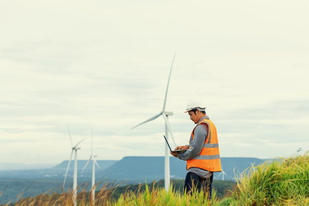 Engineer working on a wind farm atop a hill or mountain in the rural. Progressive ideal for the...