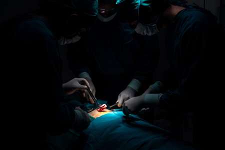 Surgical team performing surgery to patient in sterile operating room. In a surgery room lit by a...