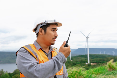 Engineer working on a wind farm atop a hill or mountain in the rural. Progressive ideal for the future production of renewable, sustainable energy. Energy generation from wind turbine.の写真素材