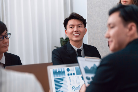 Harmony in office concept as business people analyzing dashboard paper together in workplace. Young colleagues give ideas at manager desk for discussion or strategy planning about project.の写真素材