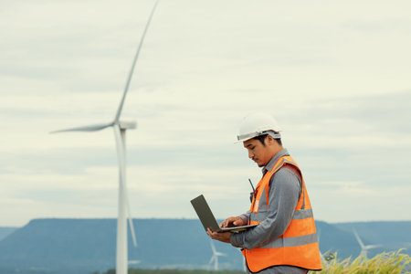 Engineer working on a wind farm atop a hill or mountain in the rural. Progressive ideal for the...