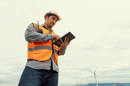Engineer working on a wind farm atop a hill or mountain in the rural. Progressive ideal for the future production of renewable, sustainable energy. Energy generation from wind turbine.の写真素材