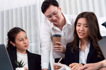 Harmony in office concept as business people analyzing dashboard paper together in workplace. Young colleagues give ideas at manager desk for discussion or strategy planning about project.の写真素材