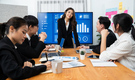 Confidence and young asian businesswoman give presentation on financial business strategy in dashboard report display on screen to colleagues in conference room meeting as harmony in workplace conceptの写真素材