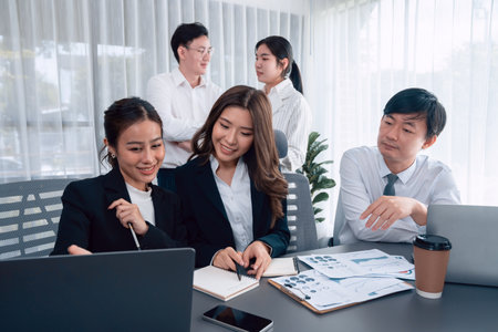 Harmony in office concept as business people analyzing dashboard paper together in workplace. Young colleagues give ideas at manager desk for discussion or strategy planning about project.の写真素材