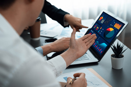 Business team analyze business analytic or business intelligence dashboard on laptop screen show graph and chart with statistic in harmony office. Analyst team meeting researching, planning strategy.の写真素材