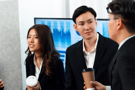 Mentor, manager with coffee advice younger colleagues in workplace. Businesspeople discussing or...